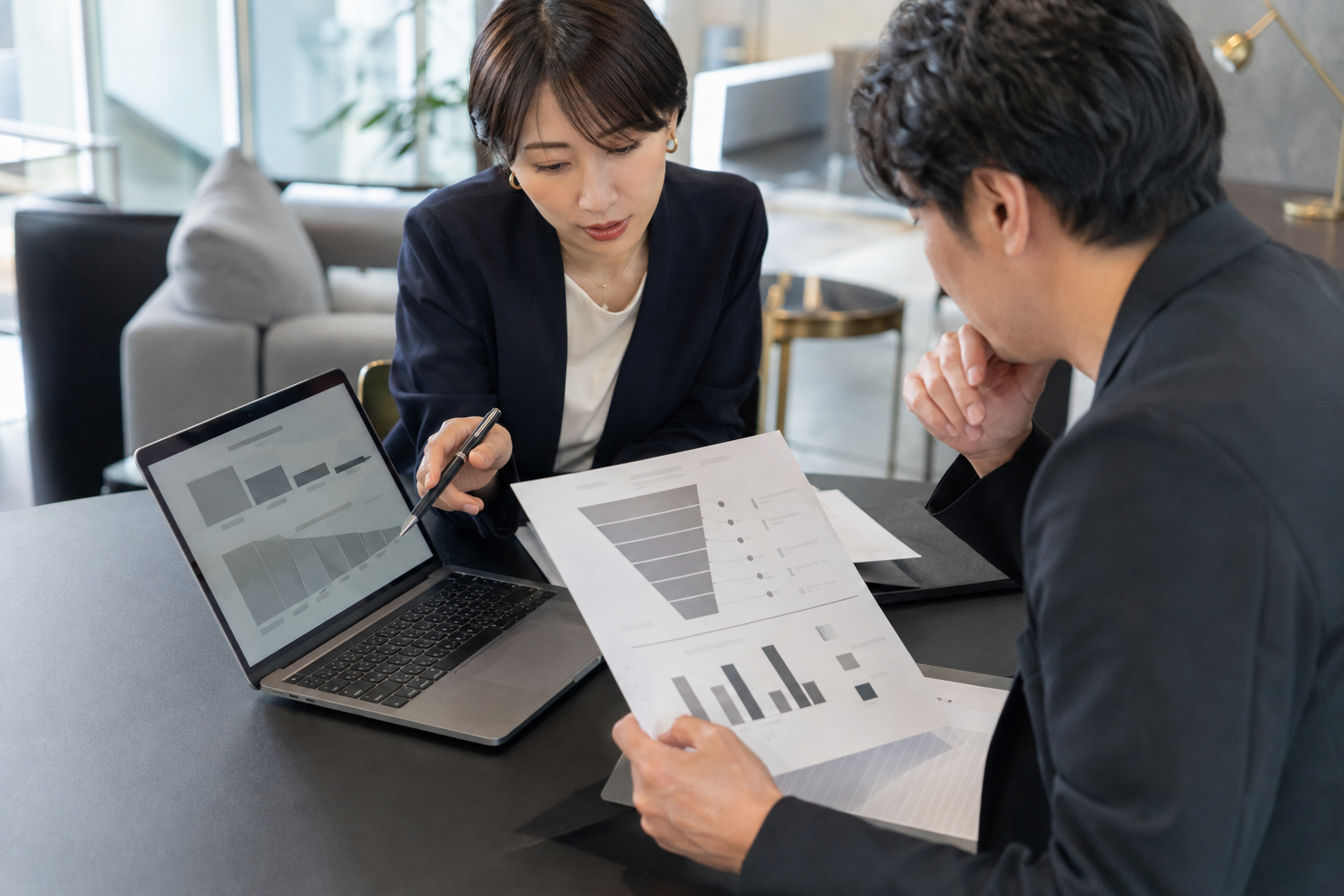 ノートパソコンと分析資料を確認する経営者とアドバイザー