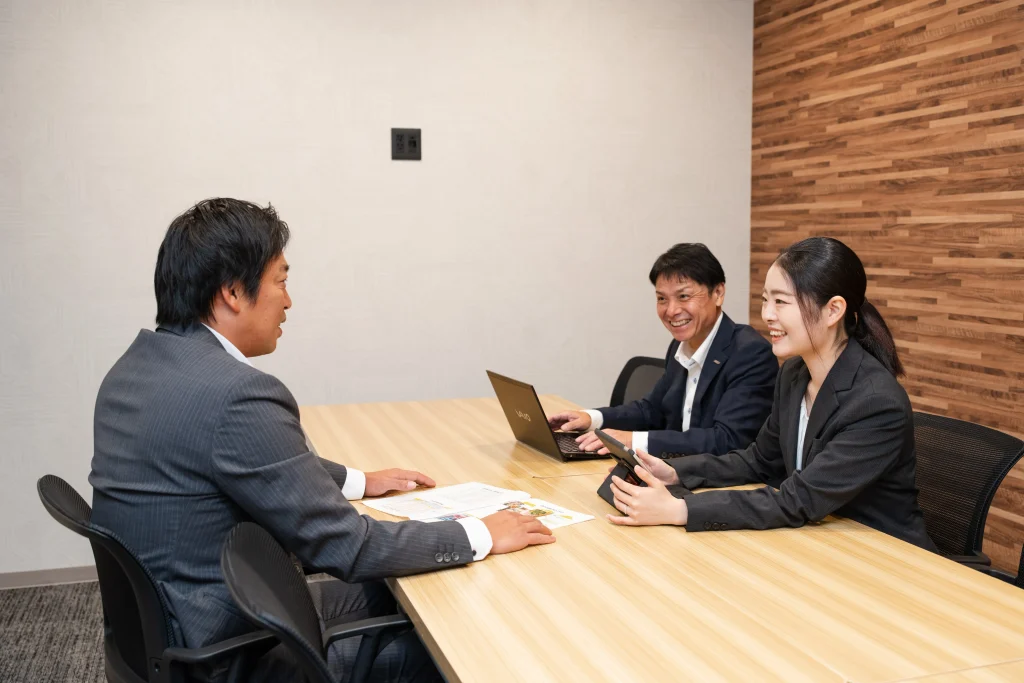 Business Park Mabuchi|大会議室で資料を囲んで話す三人