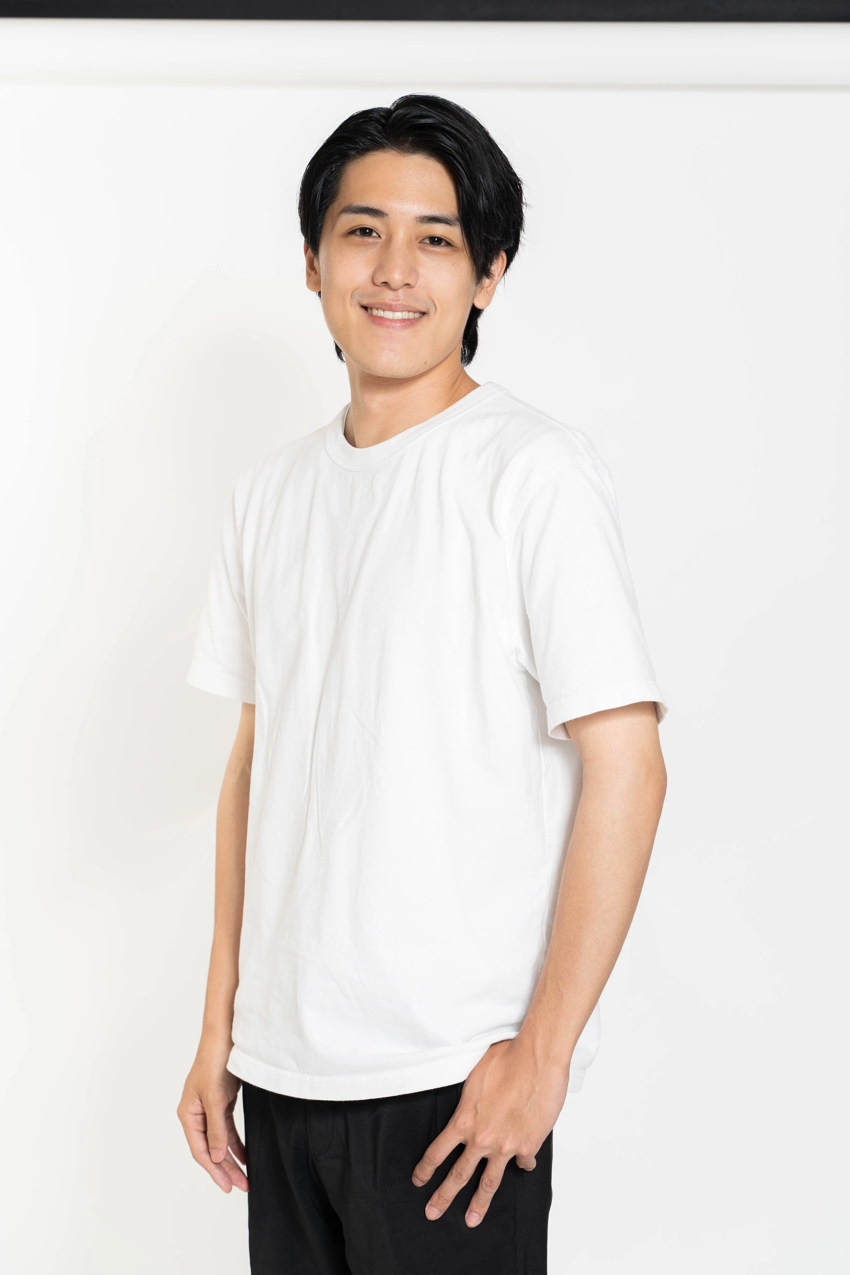 白い背景に立つ白いTシャツ姿の人物