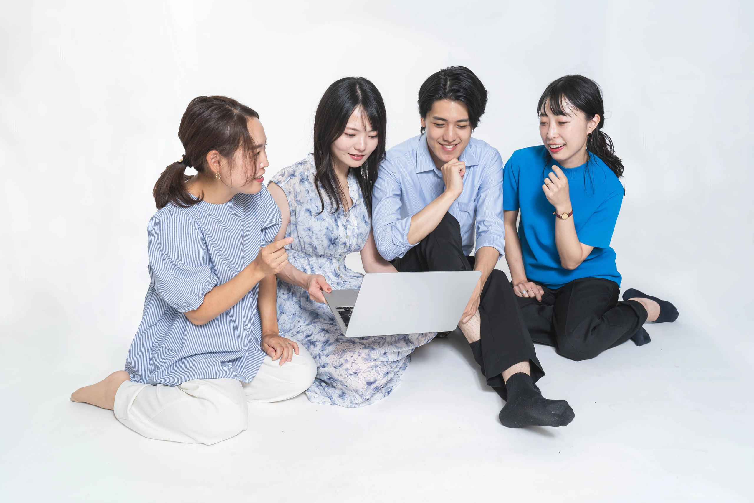 ノートパソコンを囲み会話する四人のチーム写真