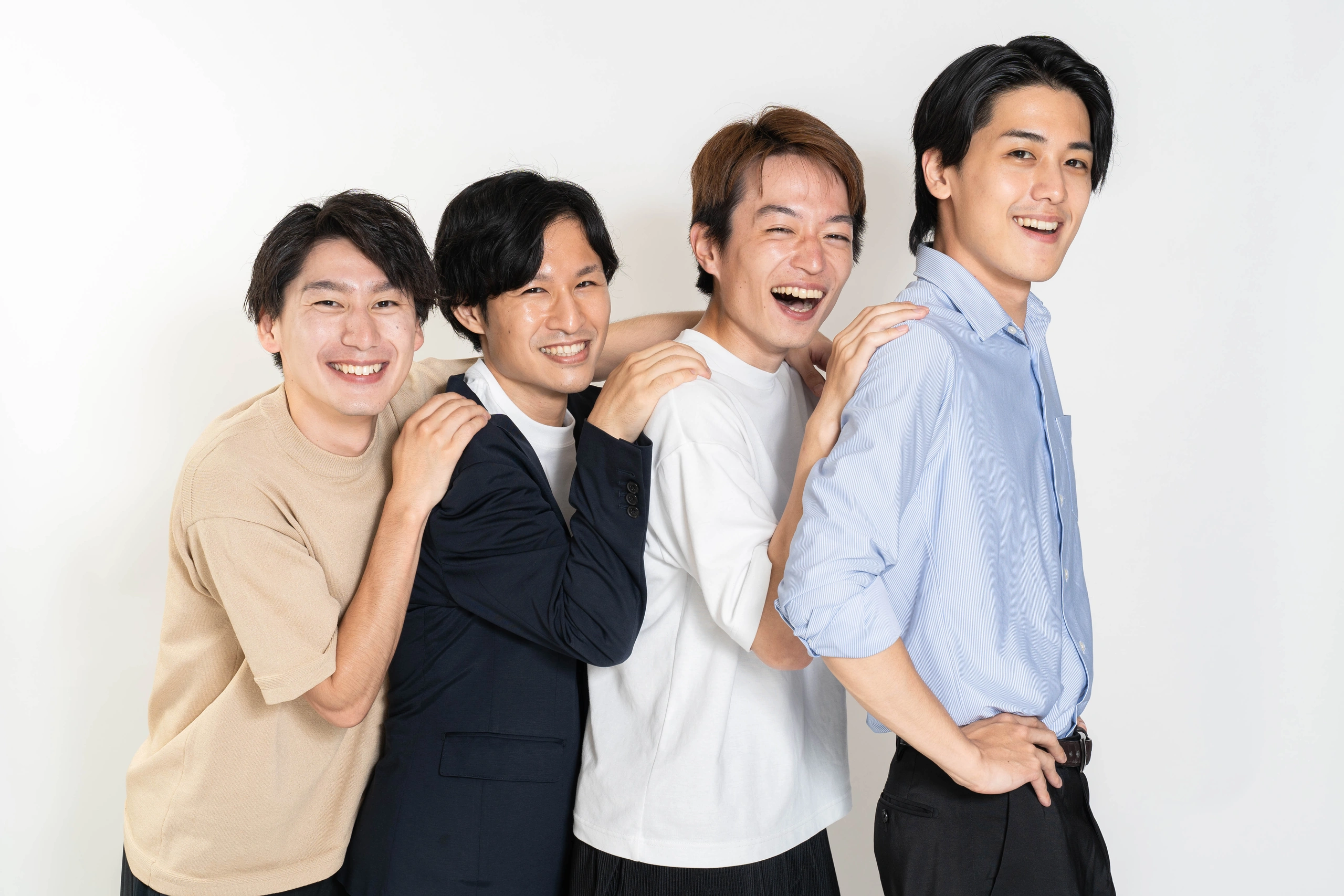 白い背景で肩を寄せ合い笑顔を見せる四人の写真